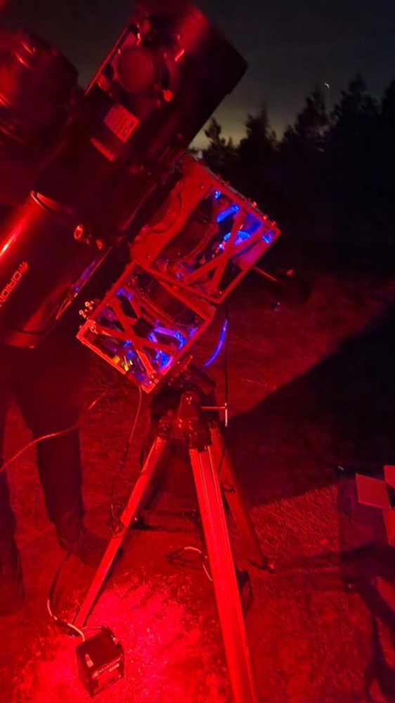 ASTRID telescope mount on a tripod outdoors at night, lit by red light.